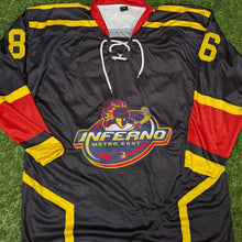 Load image into Gallery viewer, A black hockey-style jersey laid flat on artificial green turf, with yellow and red paneling, white laces, the number 8 on the right shoulder, number 6 on the left shoulder, and an Inferno Metro East logo on the chest.